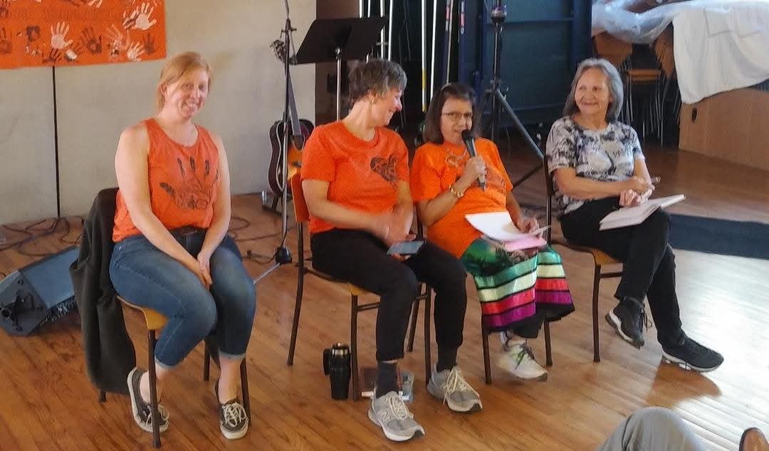 Four Sisters Walking Together members in orange shirts speaking on a panel